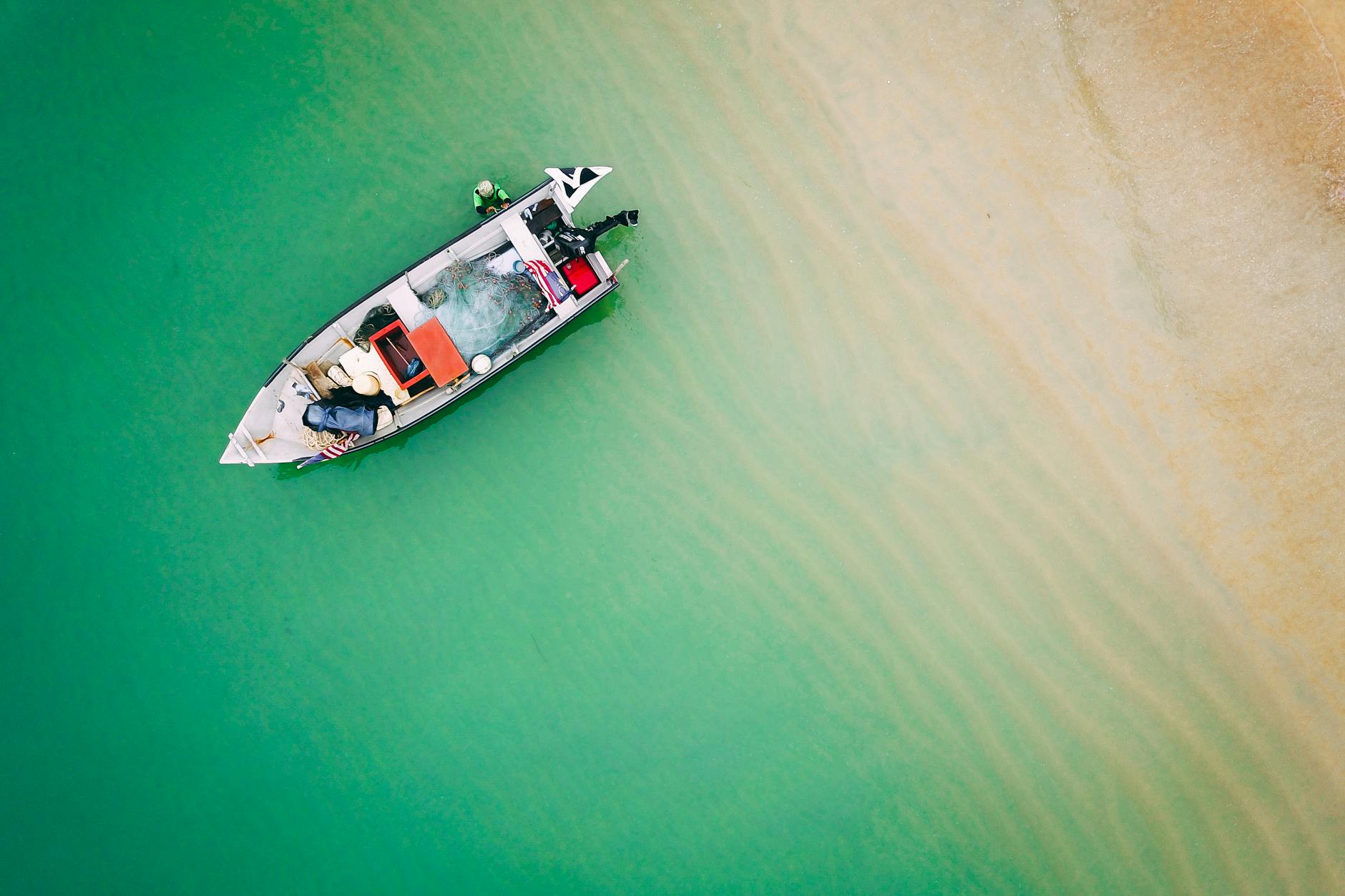 Łódź wędkarska na turkusowej wodzie przy piaszczystej plaży