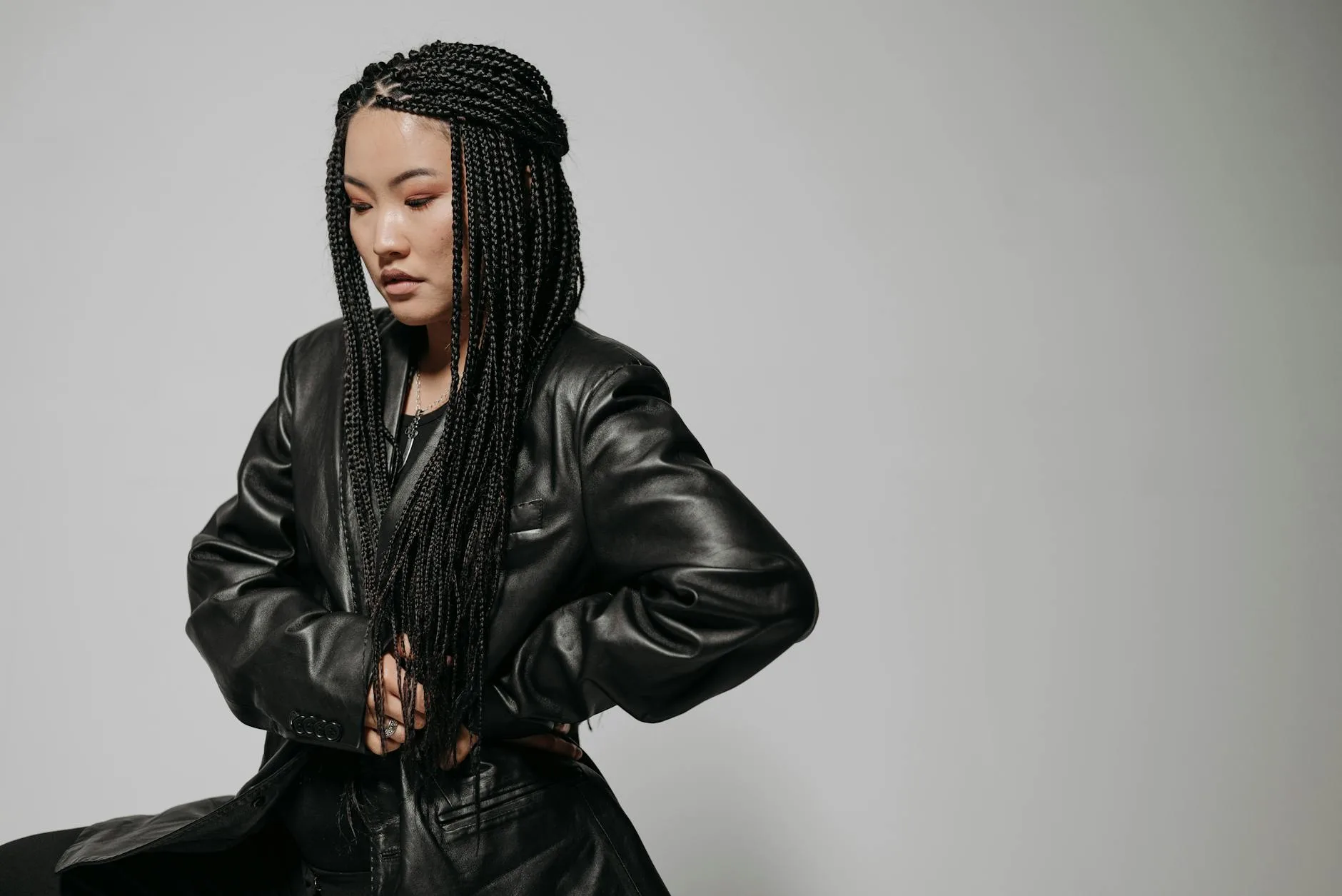 Kobieta w czarnej skórzanej kurtce pozuje na jasnym tle
