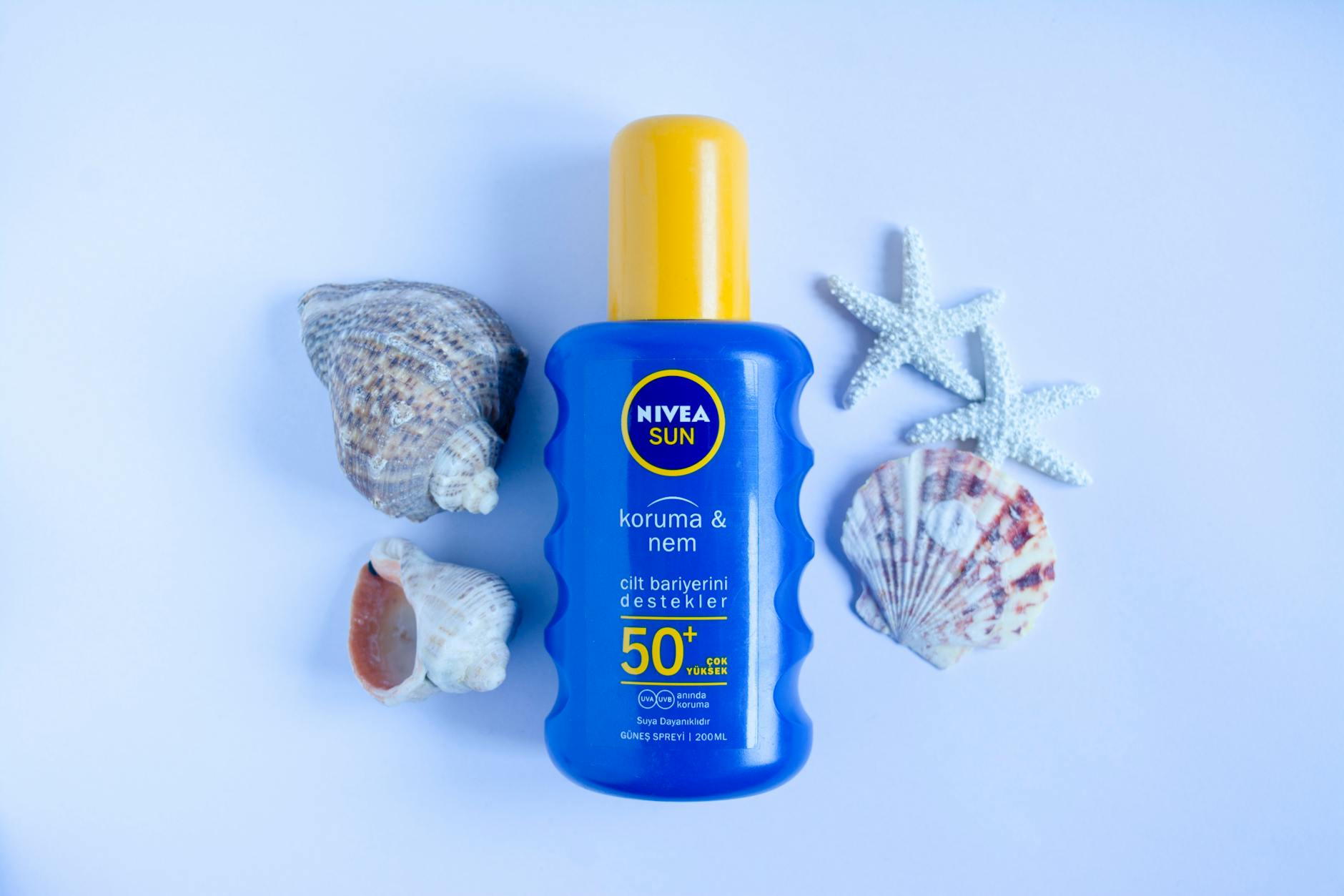 Krem do opalania Nivea Sun SPF 50+ na białym tle z muszlami i rozgwiazdą Krem do opalania Nivea Sun SPF 50+ na białym tle z muszlami i rozgwiazdą