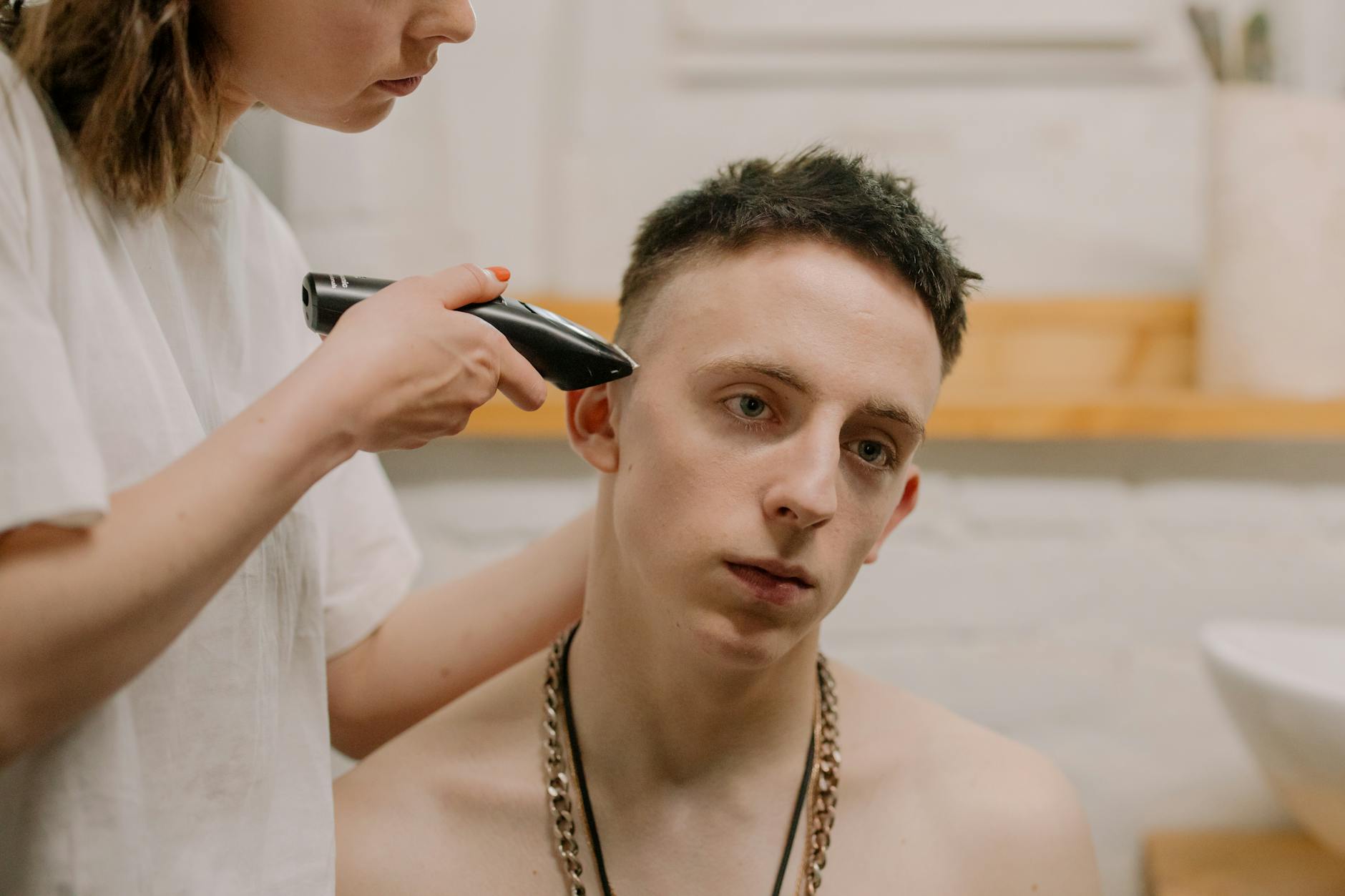 Młody mężczyzna przycina kilkudniowy zarost maszynką w domu