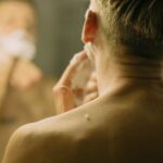 Mężczyzna goli szyję maszynką, patrząc w lustro w łazience