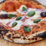 Zbliżenie na pizzę Margherita z pieca opalanego drewnem na desce