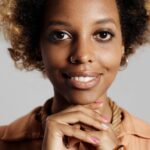 Zbliżenie uśmiechniętej kobiety z afro, prezentującej zadbaną cerę