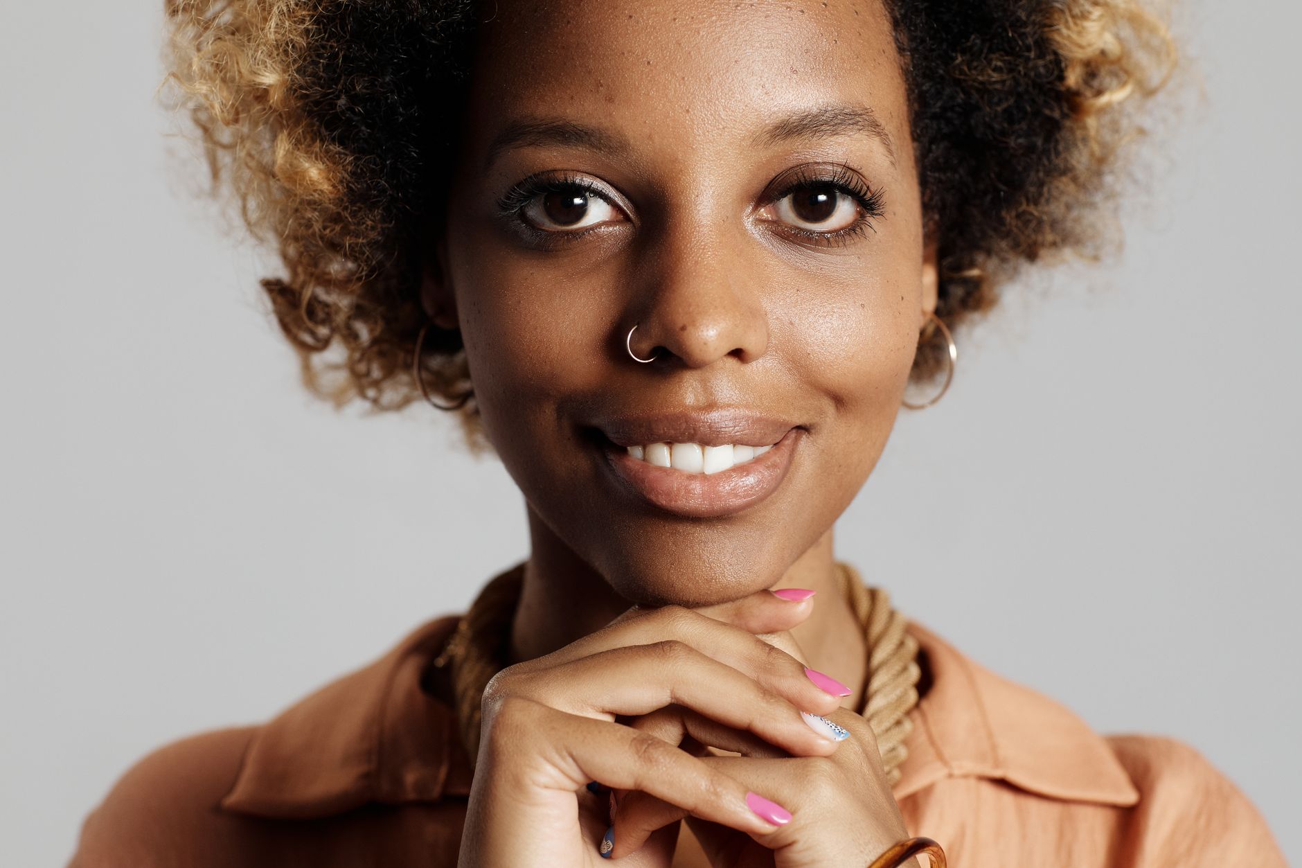 Zbliżenie uśmiechniętej kobiety z afro, prezentującej zadbaną cerę